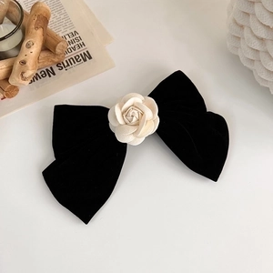 Pince à cheveux noeud en velours noir avec fleur de camélia crème sur fond blanc