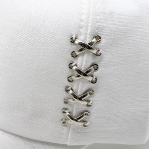 White baseball cap featuring industrial style silver metal X-shaped buckles on the side