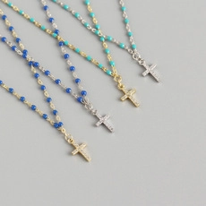 Detailed close-up of beaded cross necklaces in deep blue, turquoise, and gold finishes