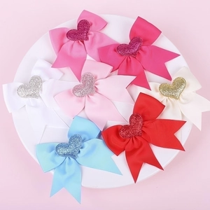 Flat lay of colorful grosgrain ribbon swallowtail bows with glittery heart centers on a plate