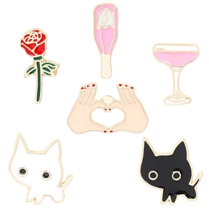 Detailed close-up of cute cartoon enamel pin set including cats and heart gestures