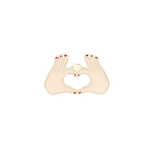 Detail of heart shape hand gesture enamel brooch with cream finish and red nails