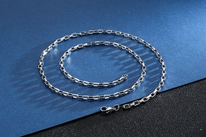 Detail of silver stainless steel box chain necklace with lobster clasp on dark background