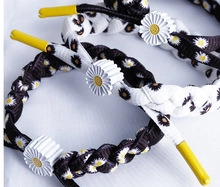 Macro view of woven daisy bracelet featuring black and white floral fabric with metal ends