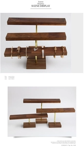 Detail of walnut wood jewelry display stand with gold metal bar for necklaces