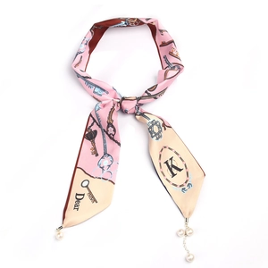 Gros plan d'un foulard en soie rose avec motifs de clés et perles élégantes