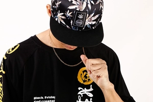 Detail of a thick gold-plated flat link chain necklace worn on a black graphic t-shirt