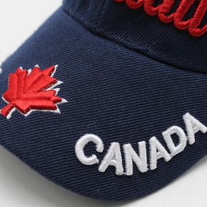 Detailed macro view of 3D CANADA text and red maple leaf embroidery on navy cotton cap