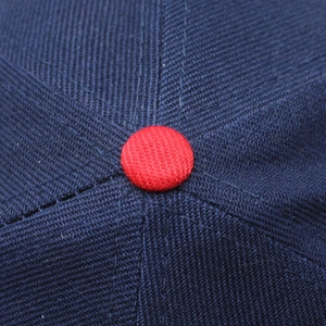 Close-up of navy blue twill fabric and red button detail on a Canada baseball cap