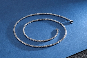 Close-up of polished stainless steel dragon bone chain necklace on blue background