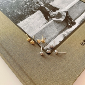 Detail of 925 sterling silver stud earrings with irregular lava texture on vintage paper