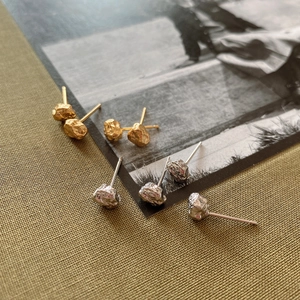 Macro shot showing irregular lava texture earrings in gold and silver metallic finish