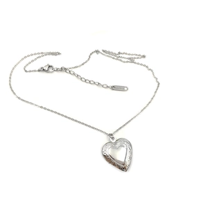 Macro shot of silver heart locket pendant with floral relief and K18 hallmark on clasp