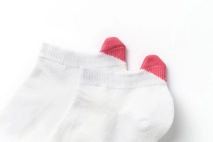 Detail of white cotton low cut socks with vibrant pink heel tabs and rib knit texture