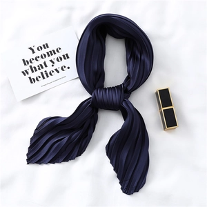 Detailed texture of pleated navy blue satin scarf with elegant crinkle finish on white surface