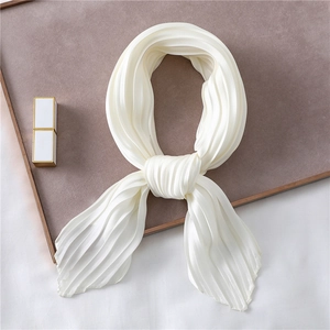 Close-up of pleated white satin neck scarf with silk texture on a display tray