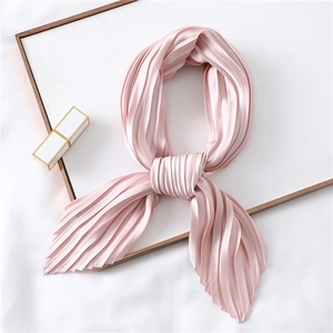Elegant pleated light pink silk scarf arranged in a heart shape on a minimalist background