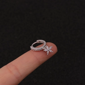 Silver hoop earrings with sparkling zircon flower pendant shown on a fingertip