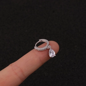 Macro shot of a silver lightning drop earring with sparkling zircon held on a finger