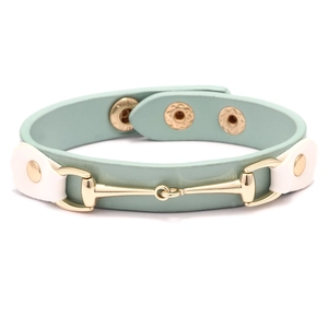 Détail du bracelet en cuir vert clair avec mors doré et boutons-pression ajustables