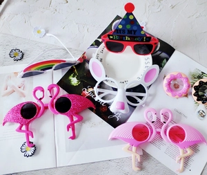 Close-up of funny daisy and flamingo party sunglasses set on decorative background