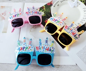 Close-up of three colorful Happy Birthday novelty glasses in pink, yellow, and blue plastic