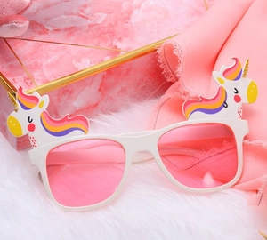 Close-up of white unicorn party sunglasses with pink lenses on a plush background