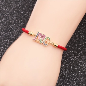 Detail eines roten Armbands mit goldenem LOVE-Herz-Anhänger und bunten Zirkoniasteinen