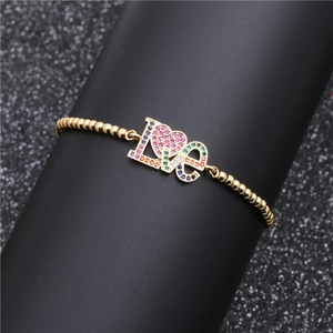 Dettaglio del bracciale LOVE dorato con zirconi colorati su espositore nero