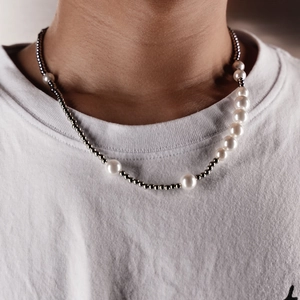 Detail shot of a minimalist necklace featuring white pearls and silver steel beads