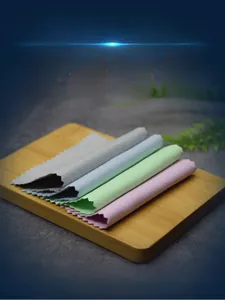 Microfiber jewelry polishing cloths in four colors layered on a bamboo tray background