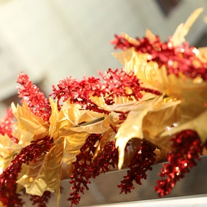 Christmas decoration featuring golden leaves and red glitter berries on a festive vine wreath