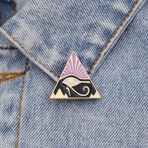 Golden Eye of Horus enamel pin with purple and black details on blue denim jacket collar