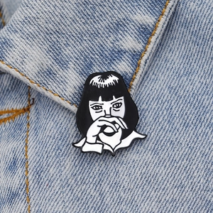 Close-up of a stylish black and white enamel girl brooch pinned on a denim jacket lapel