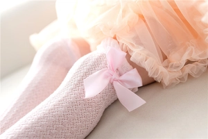 Detail of pink mesh baby socks with silk bow and breathable hollow knit texture