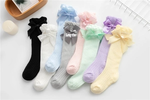 Close-up of breathable mesh baby socks with elegant lace ruffles and satin bows