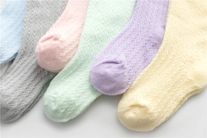 Macro detail of breathable mesh knit baby socks in pastel macaron colors for summer