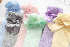 Close-up of children mesh socks with ruffle cuffs and delicate silk bow details