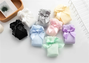 Detail of mesh knit baby socks featuring oversized satin bows in various pastel colors