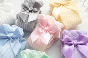 Detailed close-up of macaron colored baby socks with breathable mesh and satin bows
