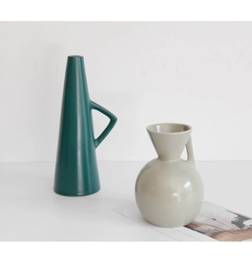 Detail of dark green geometric and beige rounded ceramic vases on a clean white surface