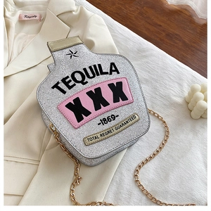 Macro shot of silver glitter tequila bottle-shaped crossbody bag on white fabric