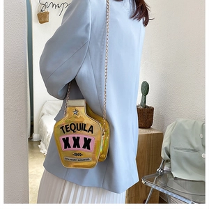 Golden tequila bottle bag with sequins and chain strap shown on model in a room
