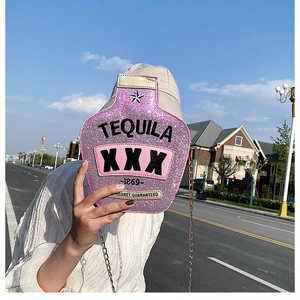 Close-up of pink glitter tequila bottle shaped crossbody bag with silver chain strap