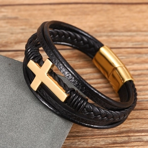 Detailed macro of black layered leather bracelet with golden cross and magnetic clasp