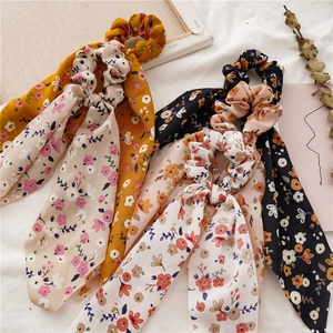 Detailed view of floral chiffon scrunchies with long ribbons in three various colors