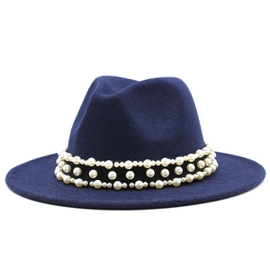 Détail d'un chapeau fedora bleu marine orné de trois rangées de perles blanches sur ruban