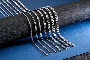 Macro detail of various widths of polished stainless steel Cuban link chains on a display
