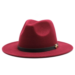 Detail of dark red wool fedora hat featuring a black leather band and gold M-shaped buckle