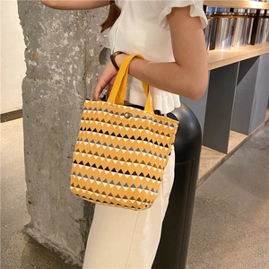 Dettaglio borsa a mano in maglia gialla con motivi geometrici blu e chiusura a scatto